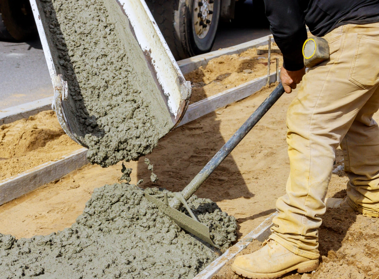 worker pouring some concrete mix on a space with dirt